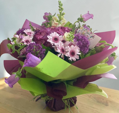 Lavender Garden - A charming and whimsical arrangement in soft purple tones, accented with fresh greenery and wrapped in vibrant contrasting paper. With its relaxed, garden-inspired style and gentle color palette, this bouquet brings a calming yet joyful touch—perfect for thoughtful gifting or brightening any room.