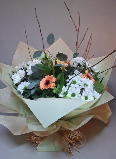 Fresh Meadow Whisper - A light and airy arrangement blending crisp whites with soft peach tones, complemented by natural greenery and delicate branches for added texture. Wrapped in neutral tones, this bouquet has a fresh, modern feel with a gentle rustic touch—perfect for elegant gifting or bringing a sense of calm indoors.